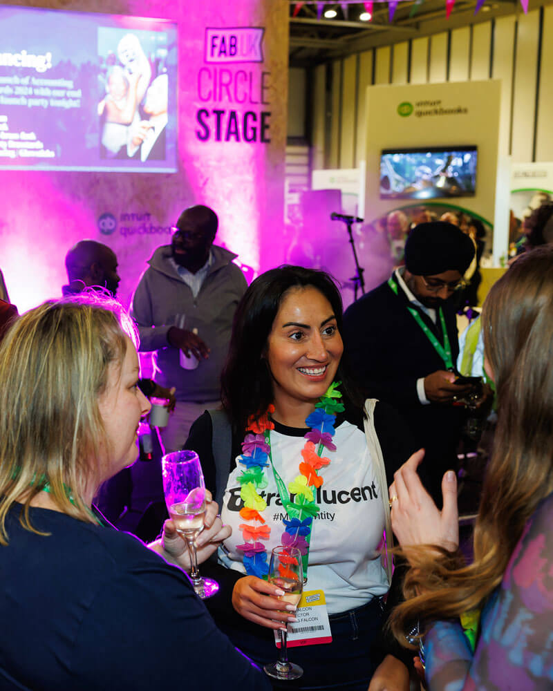 A group of people engaged in conversation and smiling at the FAB UK show, showcasing a lively event atmosphere.
